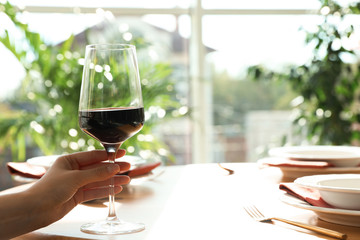 Woman with glass of wine in restaurant, closeup