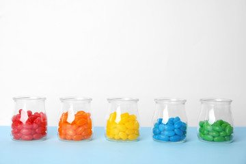 Jars of colorful jelly beans on table. Space for text