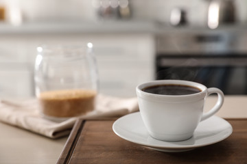 Cup of fresh coffee on table in kitchen