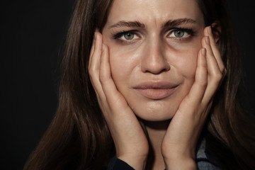 Crying young woman on dark background. Stop violence