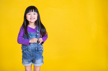 Portrait of young happy little asian girl in uniform isolated on yellow background with copy space. Education for toddler or preschool, childhood lifestyle back to school concept