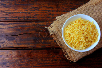 fried potato sticks in ceramic bowl on rustic wooden table with cut potatoes