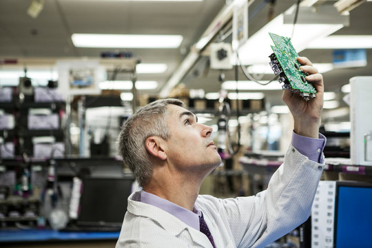 Side view of technician examining circuit board in laboratory
