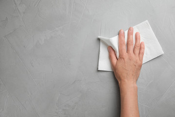 Woman wiping stone surface with paper towel, top view. Space for text
