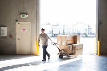 Worker using pallet jack in warehouse