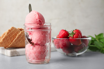 Delicious pink ice cream served with strawberries on grey table