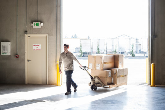 Worker using pallet jack in warehouse