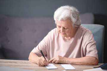 Portrait of senior woman filling out lottery ticket at table
