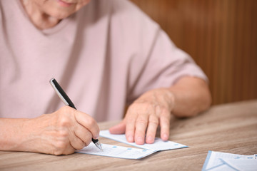 Senior woman filling out lottery ticket at table, closeup