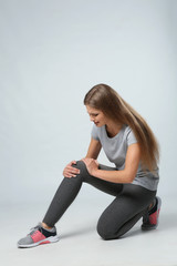 Fototapeta premium Full length portrait of sportswoman having knee problems on grey background