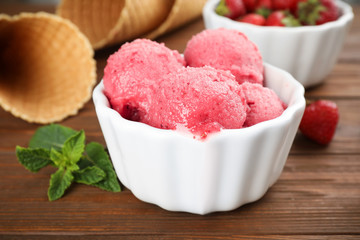 Bowl with delicious strawberry ice cream on wooden table, closeup