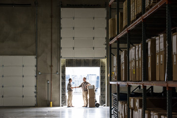 Workers shaking hands while standing in warehouse