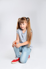 Full length portrait of little girl suffering from knee problems on grey background