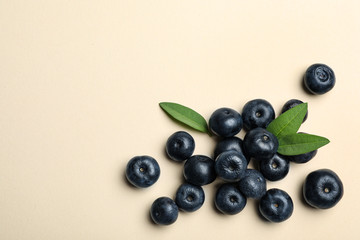 Fresh acai berries with leaves on beige background, flat lay. Space for text