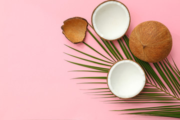 Obraz na płótnie Canvas Fresh coconuts and palm leaf on pink background, flat lay. Space for text