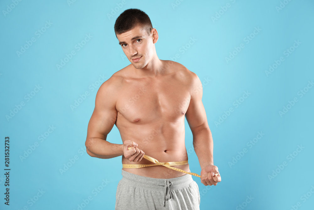 Sticker Young man with slim body using measuring tape on light blue background