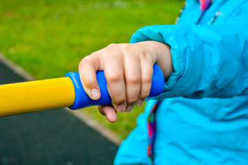 Child hand holding handle of children sports equipment on playground