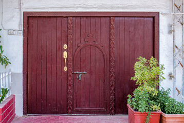 Old, retro style maroon hatch door with matching color wooden frame with intricate art craftsmanship. From Muscat, Oman.