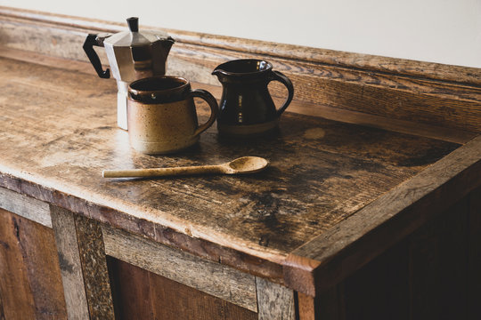 Close up of espresso machine, jug, mug spoon on wooden cabinet