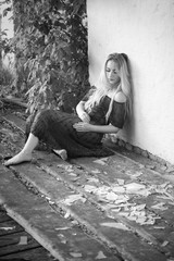 Young beautiful woman sits on a wooden floor near the splinters of a broken window. Black and white photography