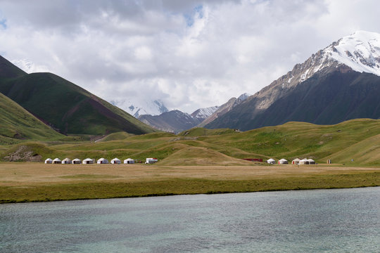 Traditional yurts on grassy landscape with mountains in background