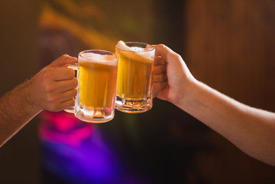 Two people toasting with mugs full of chopp