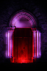 Lightpainting session in night outside. Wooden door of a church  with illuminated gothic sculpture...