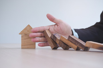Protection finance from domino effect concept. Hands stop domino effect before destroy home.