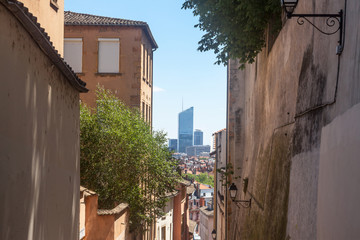 Fototapeta na wymiar Lyon skyline with its modern skyscrapers seen from the old buildings and walls of Vieux Lyon (Old Lyon) and its traditional narrow streets on Fourviere hill. Lyon is the second biggest city of France