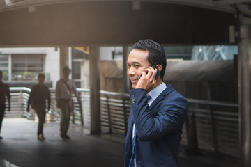 Fototapeta premium Azjatycki biznesmen mówiąc na telefon komórkowy w mieście.