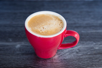 Homemade espresso flat white in bright red cup on dark wood background. Perfect with a chocolate...