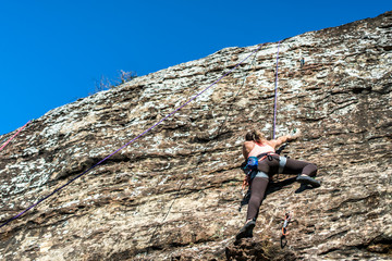 Young woman climbing on rock wall