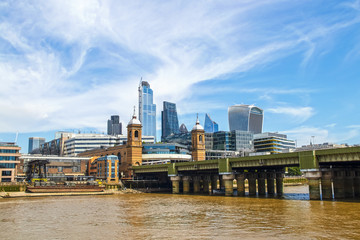 Skyline of London viewed over Thames River and London Bridge under beautiful blue sky with whispy clouds
