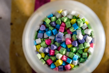 Colorful heart shaped candies inside a plastic jar viewed from above