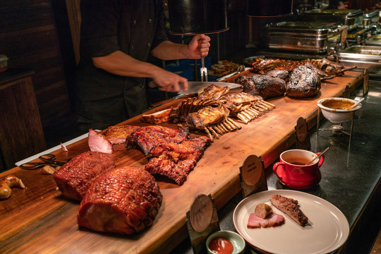 BBQ chef cutting huge grilled lamb ribs at buffet restaurant