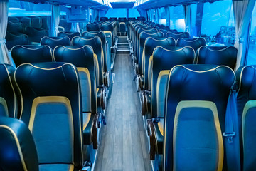 Fototapeta premium The interior of a modern passenger bus. Intercity bus. Passage between the rows of passenger seats. Seats for passengers. Comfortable long-distance people transportation. Travelling by bus.