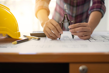 Female architect drawing blueprints in office workplace.