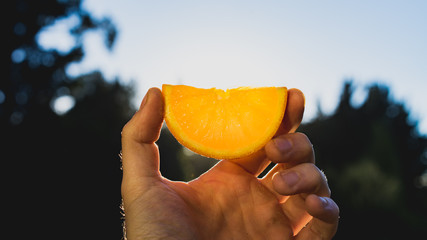 hand holding a slice of an orange