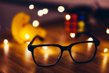 Glasses on desk with lights in the background © Dan