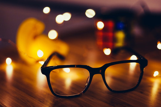 Glasses on desk with lights in the background