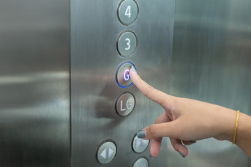 Close up waman hand press a up button of elevator.
