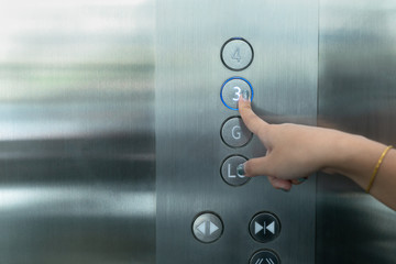 Close up waman hand press a up button of elevator.