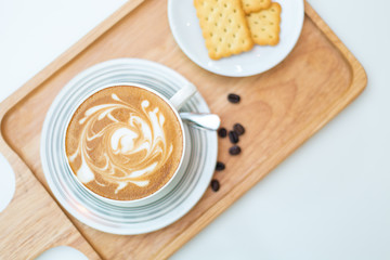 Hot coffee on background served with crackers on white plate. on top