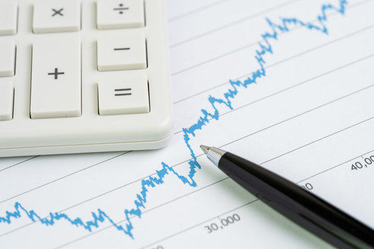 Stock price drop and growth chart with calculator and pen using as financial analysis, stock market price volatility report or information for investment