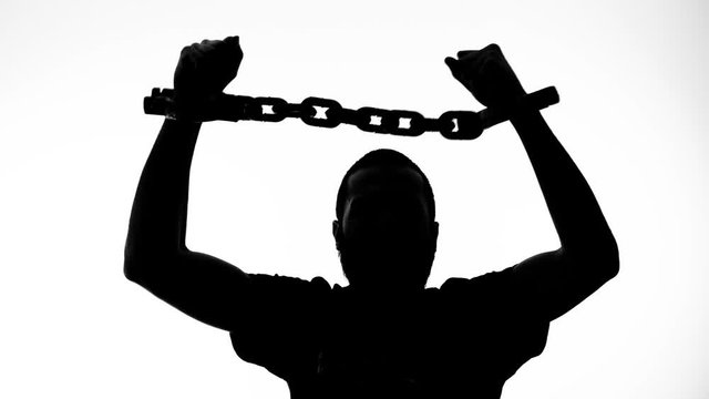 Silhouette of a chained man getting free