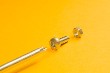 Steel screw on a yellow background