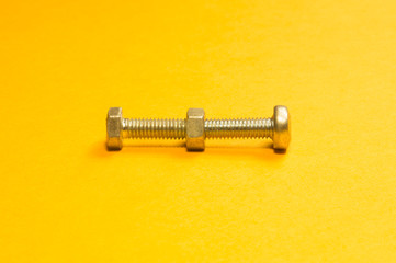 Steel screw on a yellow background