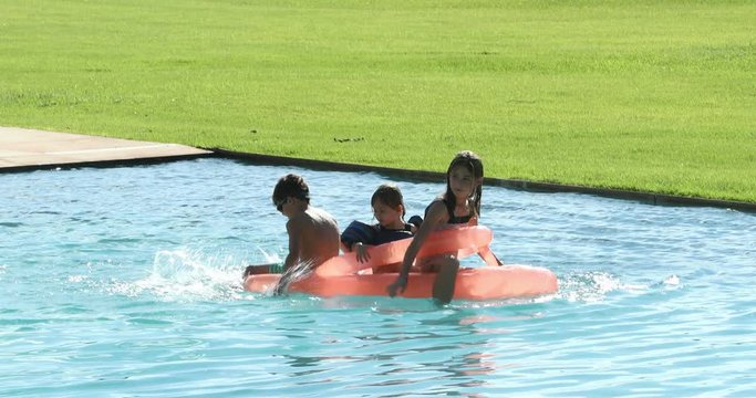 Children playing the swimming pool water on top of inflatable mattress