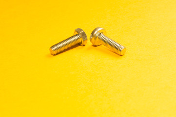 Steel screw on a yellow background