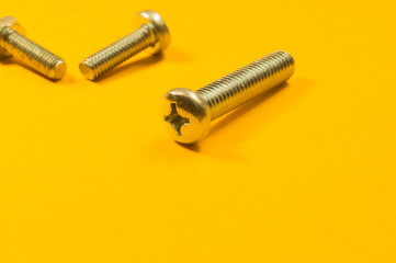 Steel screw on a yellow background